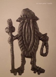 Badge of a vulva with legs dressed as a medieval pilgrim with hat, rosary and walking stick.