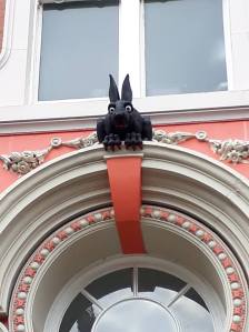 A black rabbit sculpture sits above an ornate white and pink door frame. He has blood-red nails and teeth!