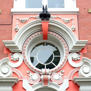 Image of black rabbit sitting atop ornately decorated pink and white door.