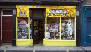Frontage of Sore THumbs Retro Games, the window is jam packed with games and a life size Stormtrooper.